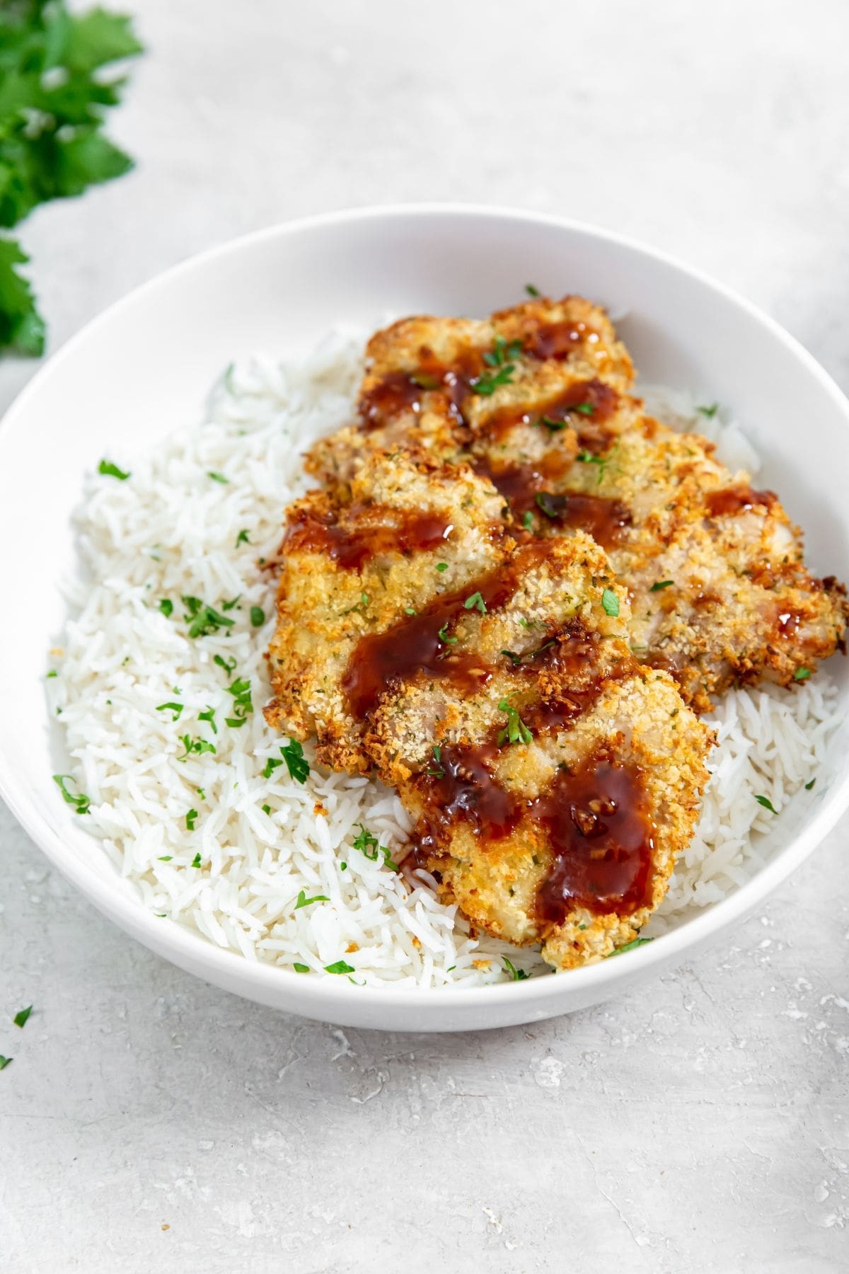 chicken and rice in a white bowl. parsley and white towel in the back