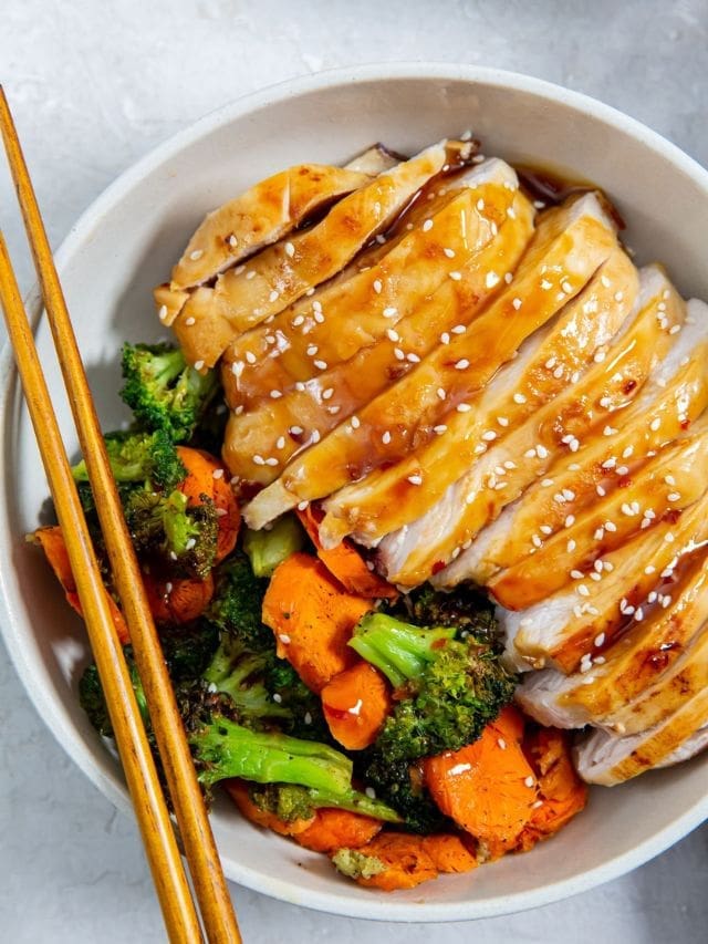 chicken and veggies in a white bowl. chopsticks on the side of the bowl