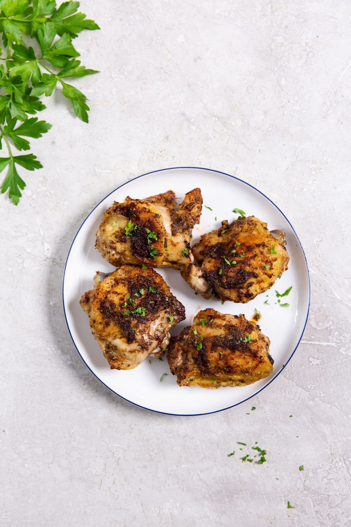 white plate with chicken on it parsley in the back