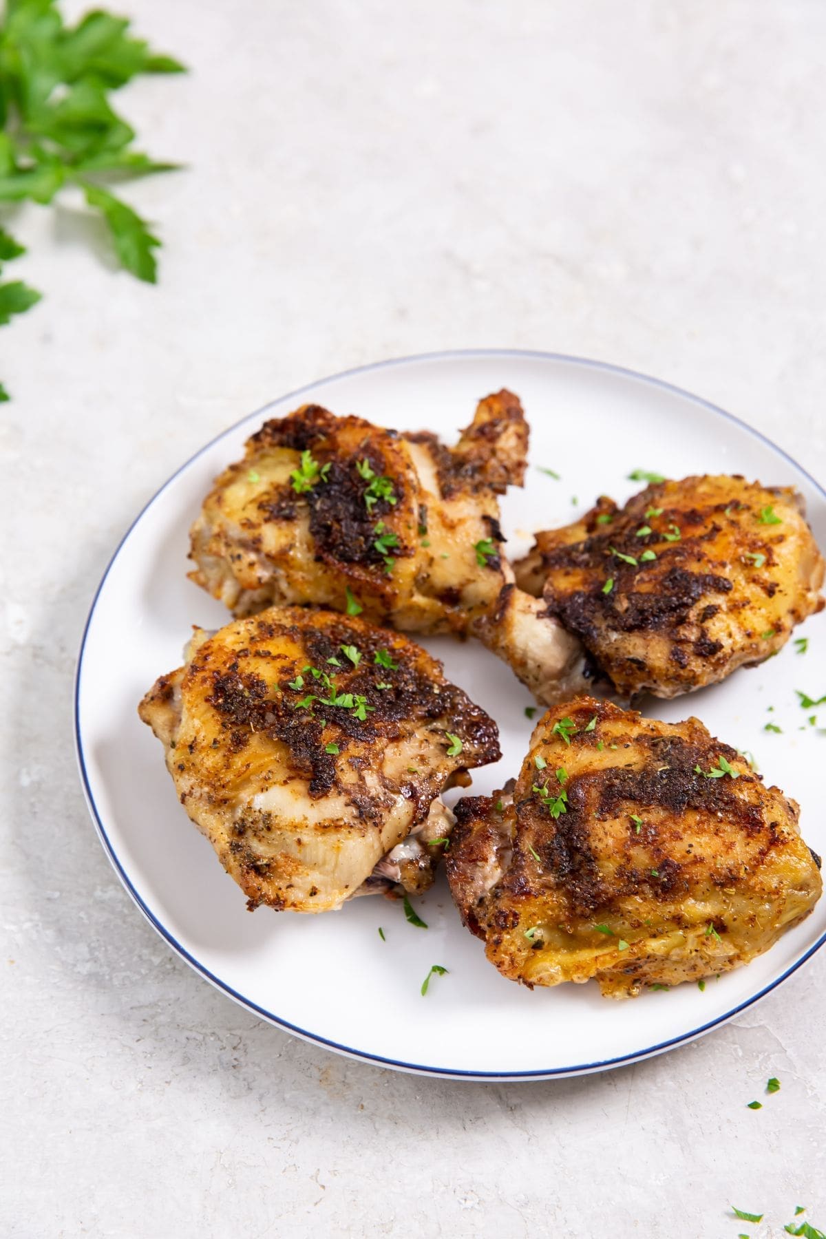 white plate with chicken on it parsley in the back