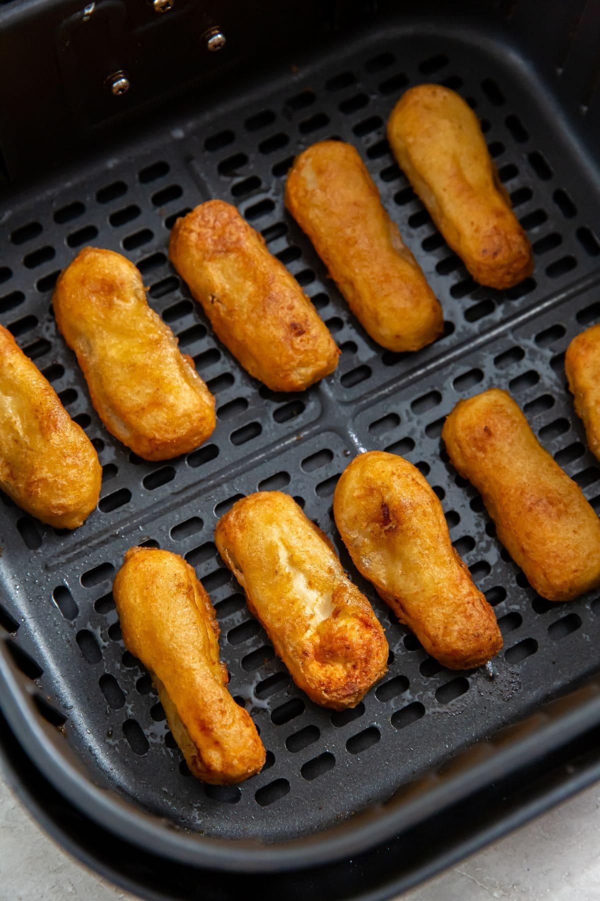 black air fryer basket with cooked chicken inside
