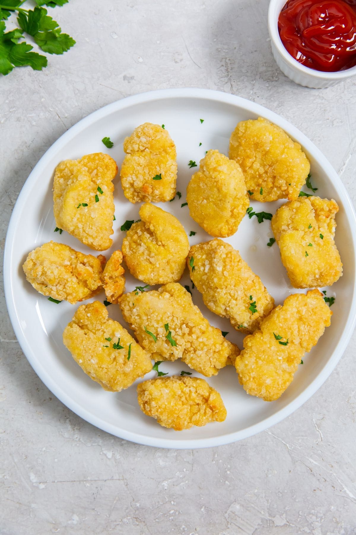 white plate with chicken on it parsley sprinkled on top