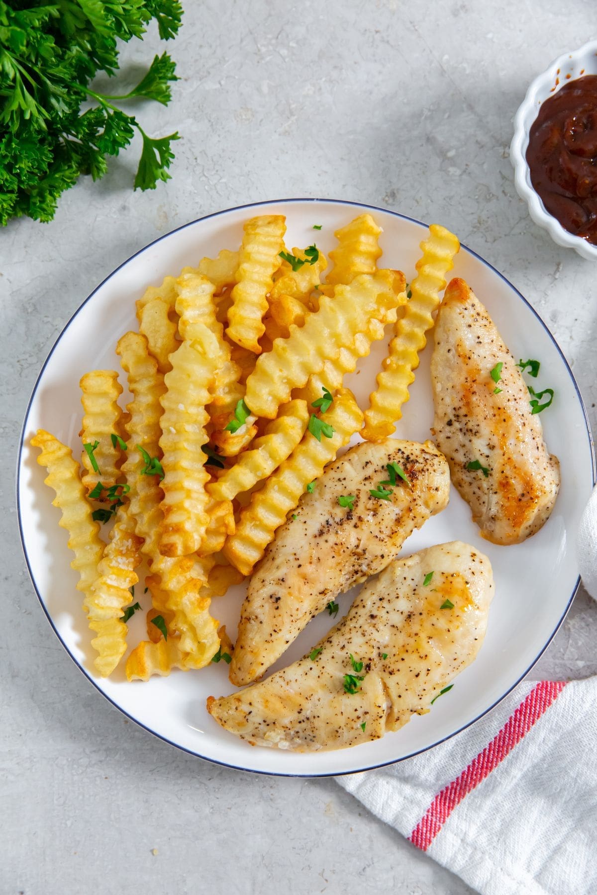 plate with chicken and fries. BBQ sauce in the back