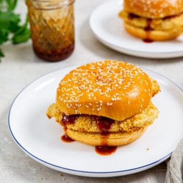 two plates with chicken sandwiches on them