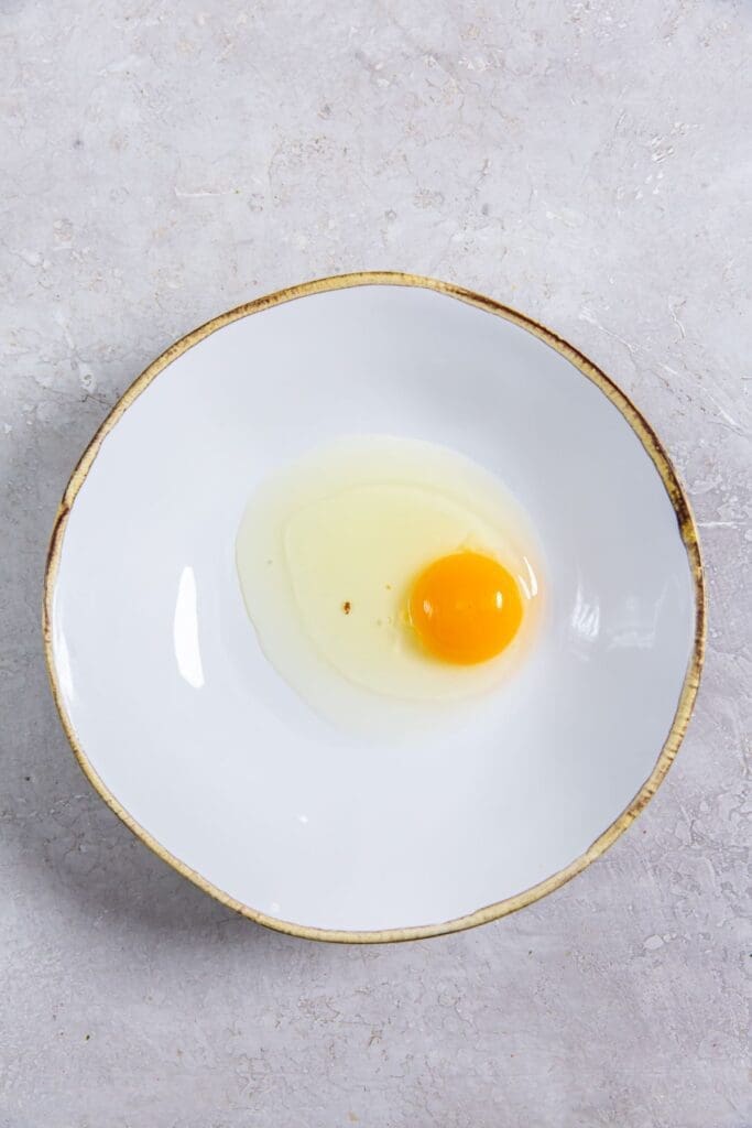 white bowl with an egg cracked inside