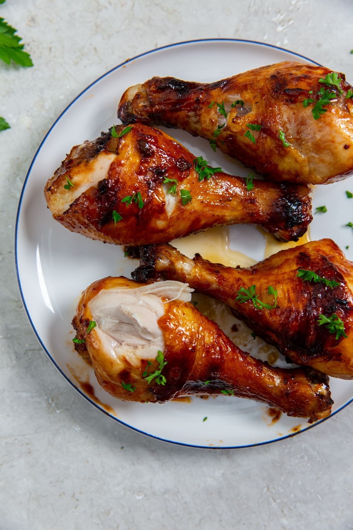 white plate with chicken on it. parsley sprinkled on top and parsley in the back