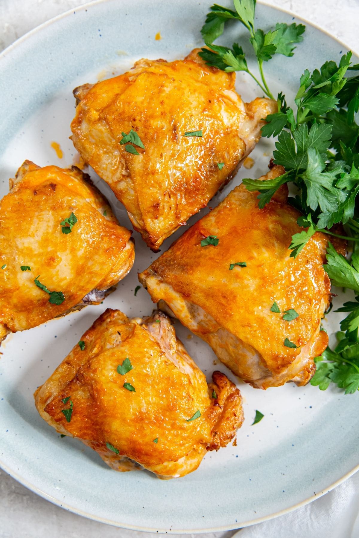 white plate with chicken and parsley on it.
