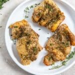 air fryer boneless chicken thighs on a white plate with herbs.