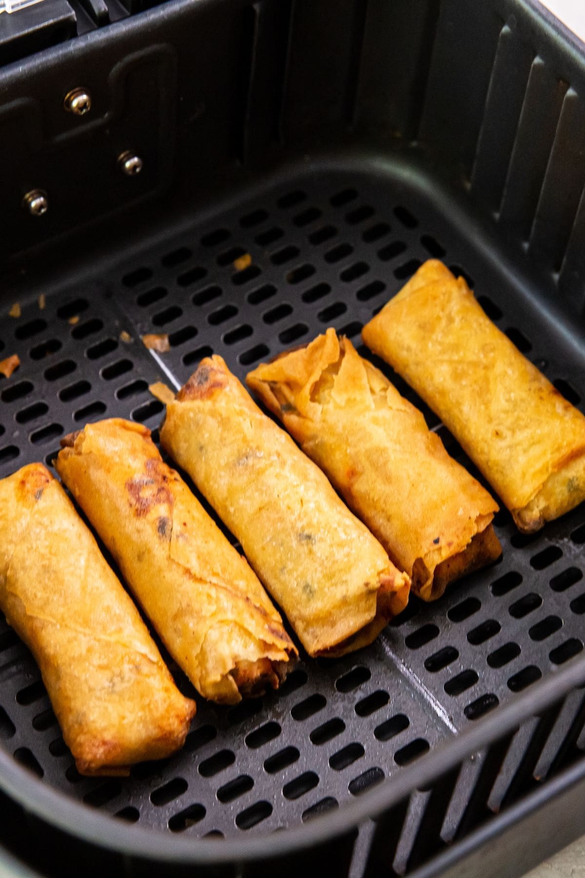 black air fryer basket with cooked chicken inside.
