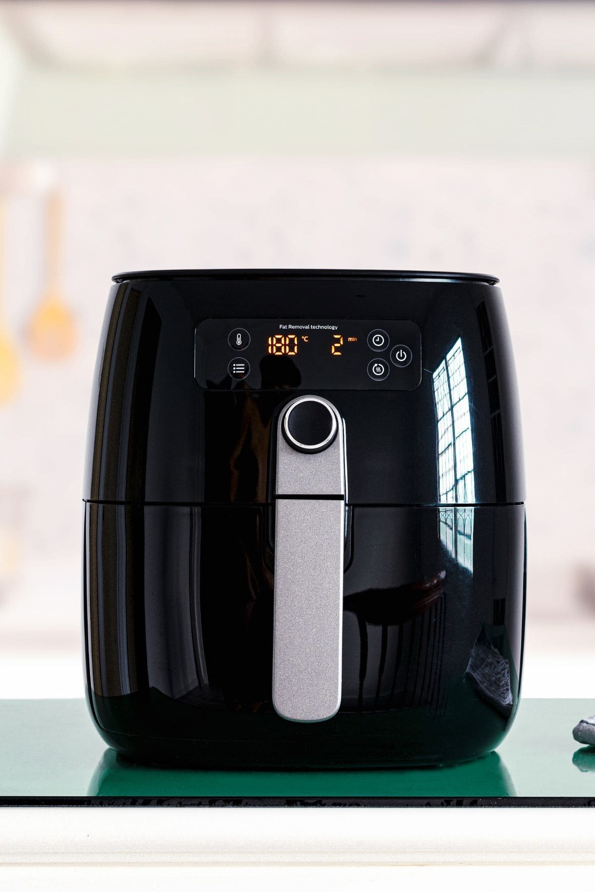 A black air fryer with accessories on a counter top.