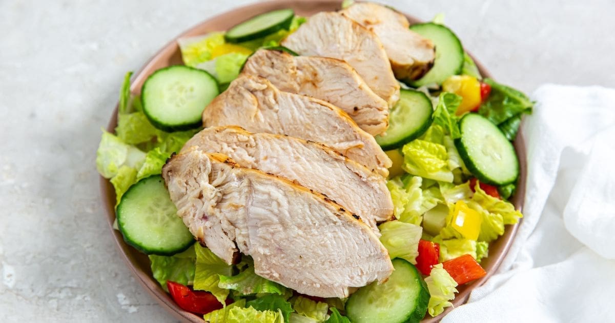 Air Fryer Italian Chicken Breast served on top of salad in a bowl.