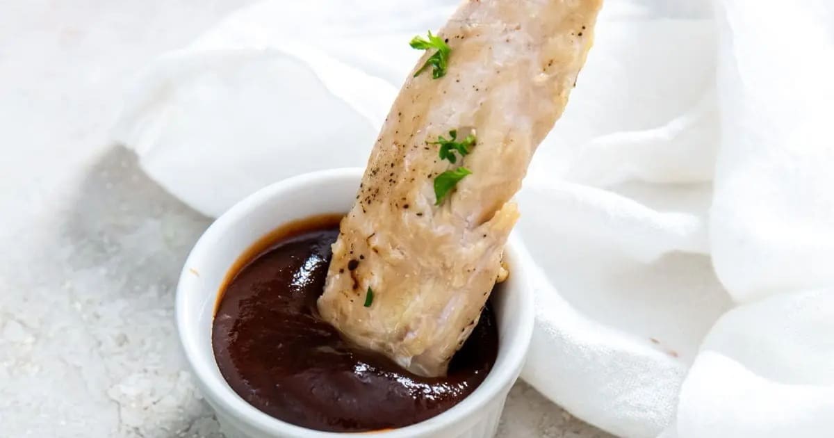 Best Chicken Air Fryer Snacks for Kids Frozen Chicken Tenders in Air Fryer Being Dipped into a Small Ramekin of BBQ Sauce