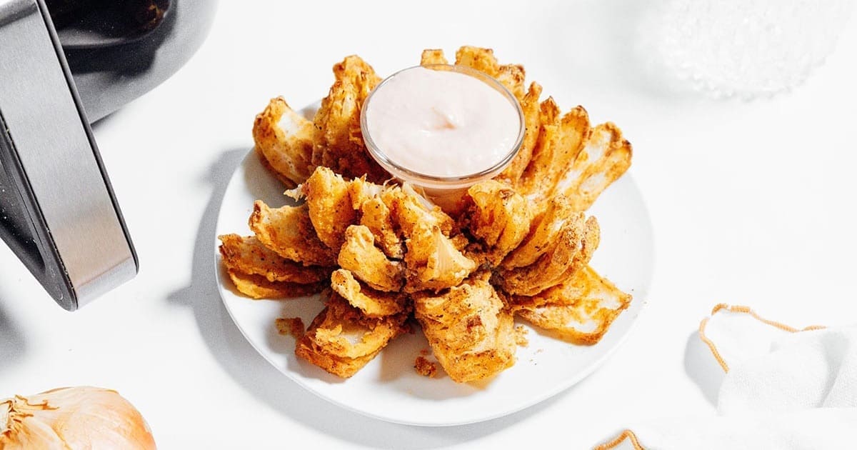Ultimate Super Bowl Air Fryer Recipe Guide Crispy Air Fryer Blooming Onion on a Plate with a Small Ramekin of Ranch Dressing